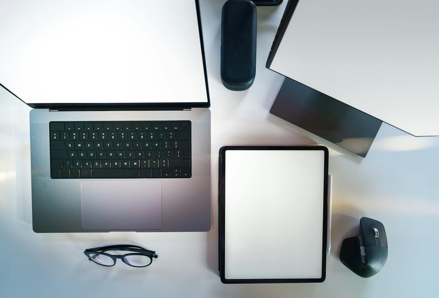 Modern digital workspace with laptop, tablet, and monitor on a white desk.